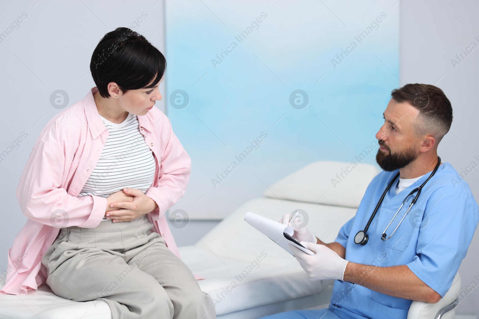 Photo of Gastroenterologist consulting patient with stomach pain in clinic