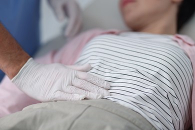 Photo of Gastroenterologist examining patient's stomach in clinic, closeup