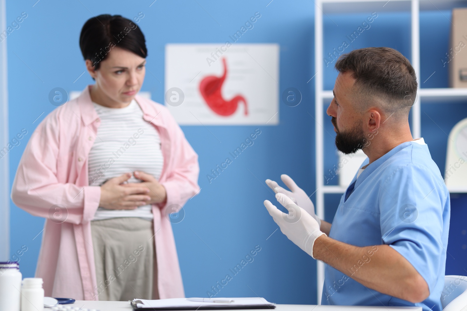 Photo of Gastroenterologist consulting patient with stomach pain in clinic, selective focus