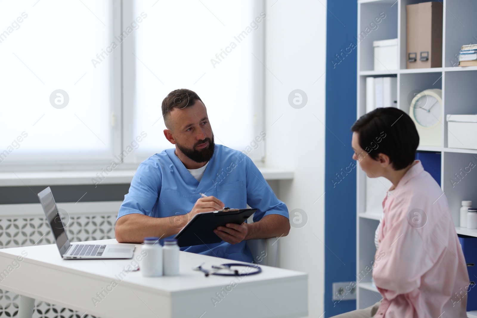 Photo of Gastroenterologist consulting patient with stomach pain in clinic