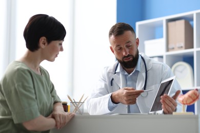 Photo of Gastroenterologist consulting patient at table in clinic