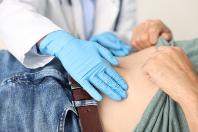 Photo of Gastroenterologist examining patient with stomach pain in clinic, closeup