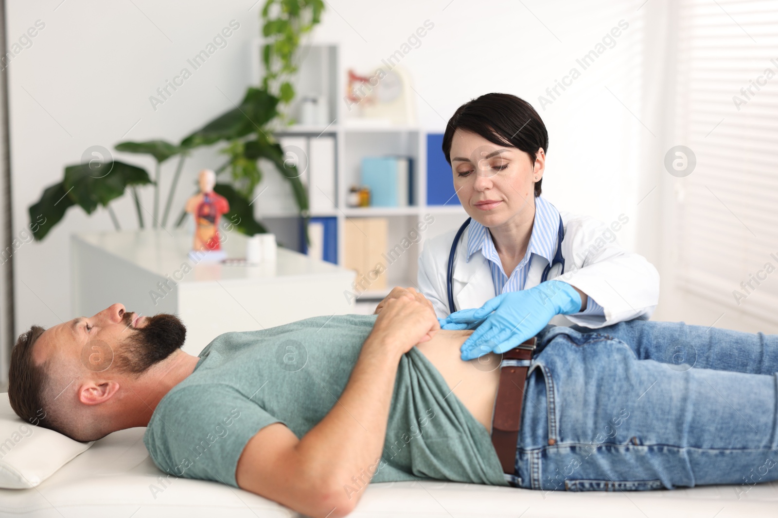 Photo of Gastroenterologist examining patient with stomach pain in clinic