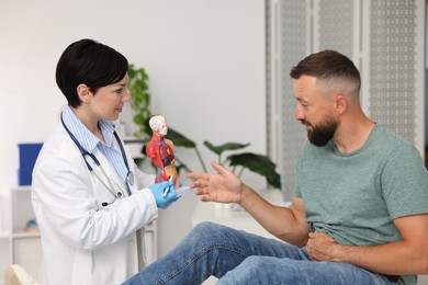 Photo of Gastroenterologist showing intestine in human anatomy mannequin to patient at clinic