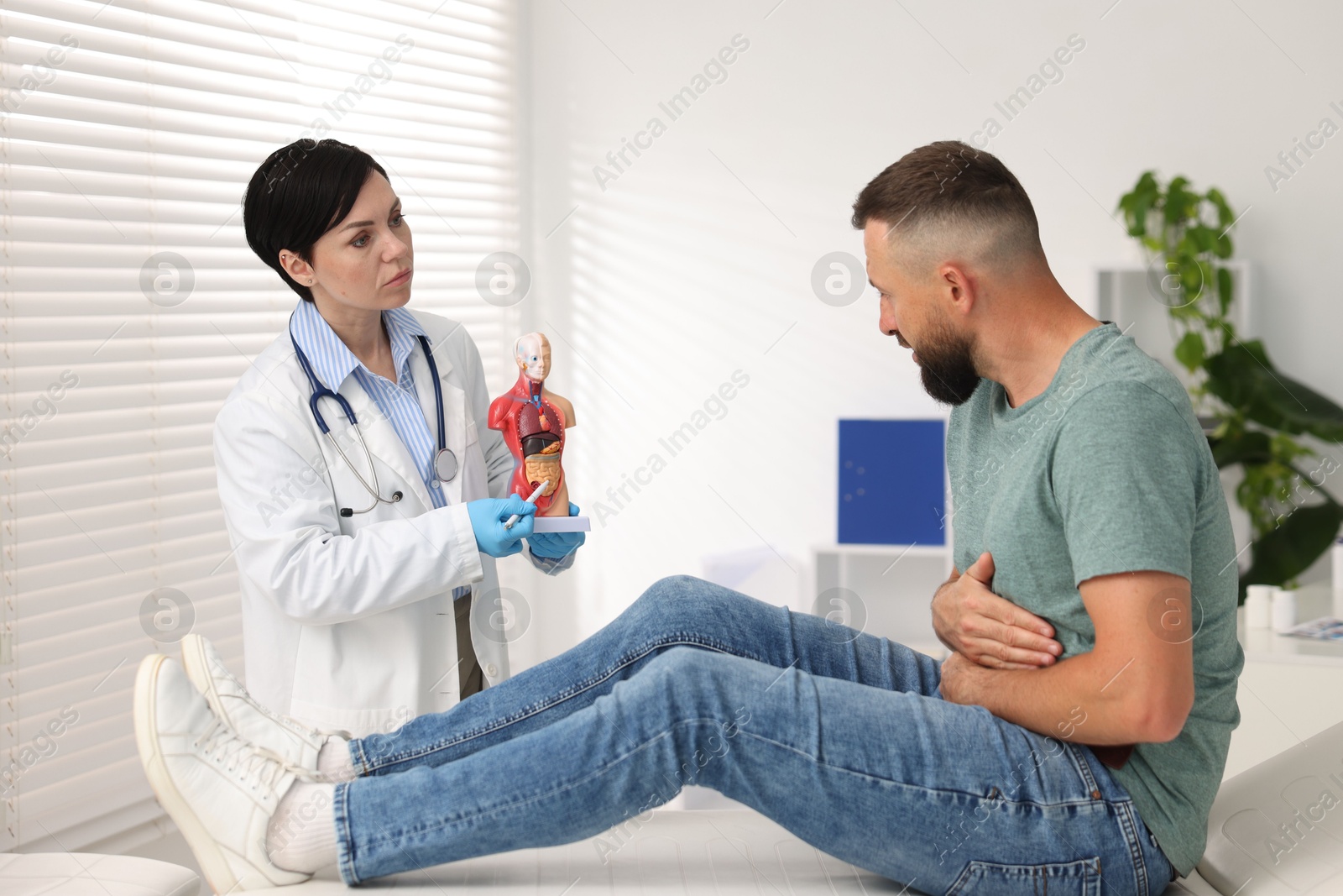 Photo of Gastroenterologist showing intestine in human anatomy mannequin to patient at clinic