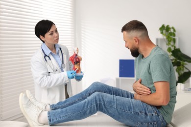 Photo of Gastroenterologist showing intestine in human anatomy mannequin to patient at clinic