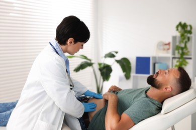 Photo of Gastroenterologist examining patient with stomach pain in clinic