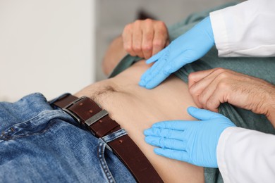 Photo of Gastroenterologist examining patient's stomach in clinic, closeup