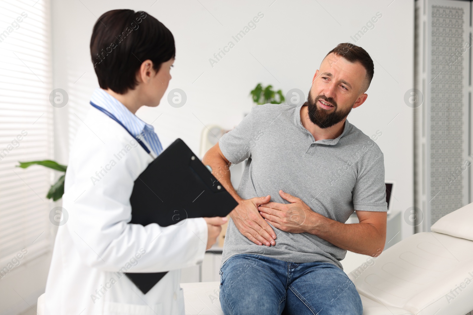 Photo of Gastroenterologist consulting patient with stomach pain in clinic