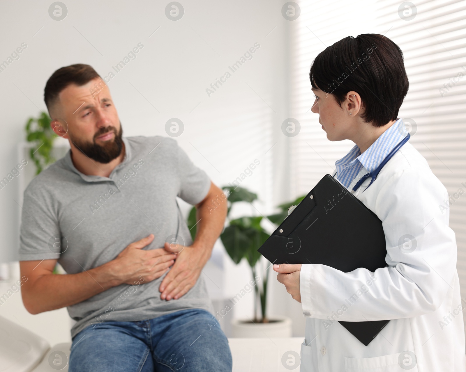 Photo of Gastroenterologist consulting patient with stomach pain in clinic