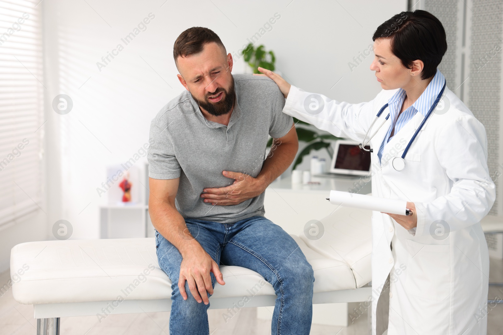 Photo of Gastroenterologist consulting patient with stomach pain in clinic