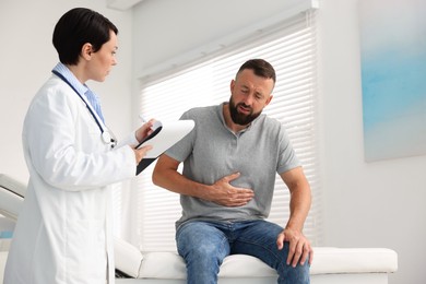 Photo of Gastroenterologist consulting patient with stomach pain in clinic, low angle view