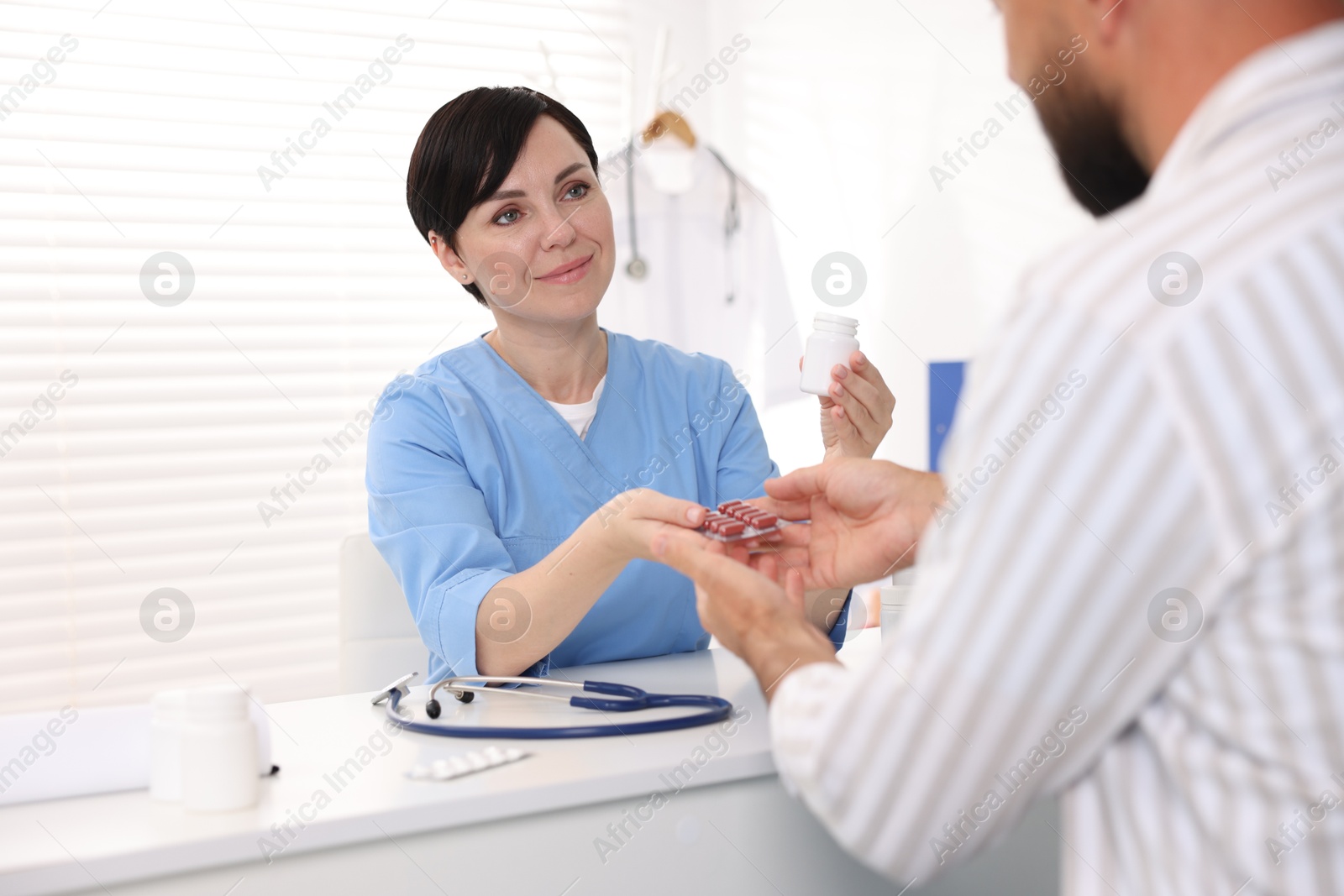 Photo of Gastroenterologist giving pills to patient at table in clinic
