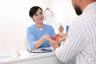 Photo of Gastroenterologist giving pills to patient at table in clinic