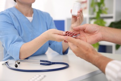 Photo of Gastroenterologist giving pills to patient at table in clinic, closeup