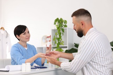 Photo of Gastroenterologist giving pills to patient at table in clinic