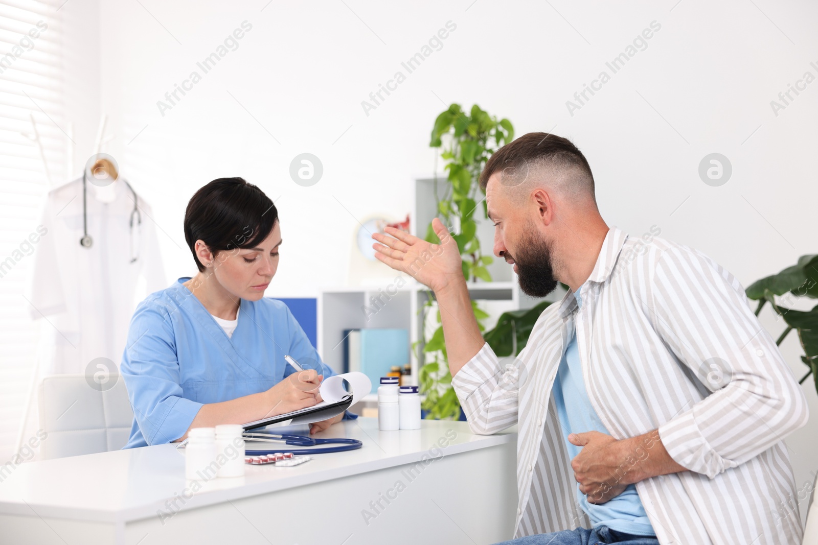 Photo of Gastroenterologist consulting patient with stomach pain in clinic