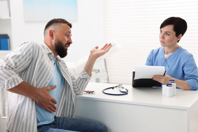 Photo of Gastroenterologist consulting patient with stomach pain in clinic