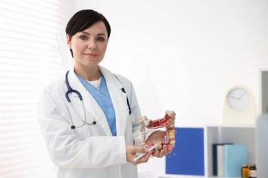Photo of Gastroenterologist showing model of large intestine in clinic. Space for text