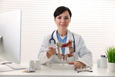 Photo of Gastroenterologist showing model of large intestine at white table in clinic