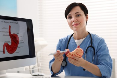 Photo of Gastroenterologist showing human stomach model in clinic