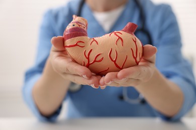 Photo of Gastroenterologist with human stomach model in clinic, closeup