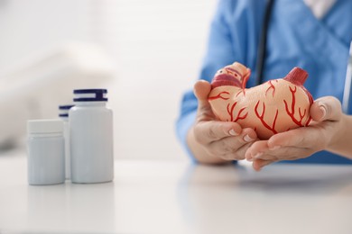 Photo of Gastroenterologist with model of stomach at white table in clinic, closeup