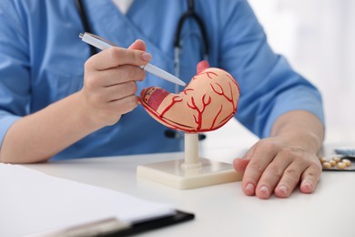 Photo of Gastroenterologist showing model of stomach at white table in clinic, closeup