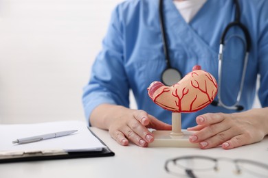 Photo of Gastroenterologist showing model of stomach at white table in clinic, closeup