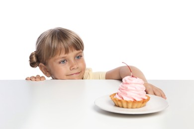 Photo of Cute little girl reaching for tasty dessert at table against white background
