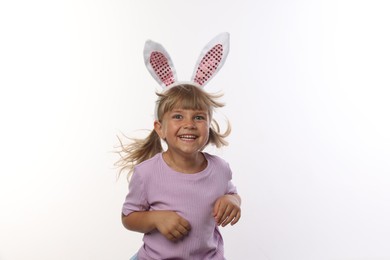 Photo of Curious little girl in bunny ears on white background