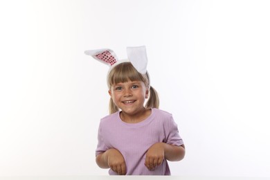 Photo of Curious little girl in bunny ears on white background