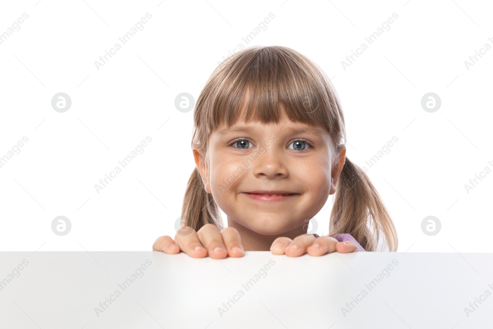 Photo of Curious little girl peeking over table against white background