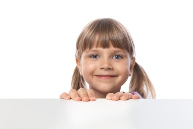 Photo of Curious little girl peeking over table against white background