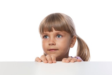 Photo of Curious little girl peeking over table against white background
