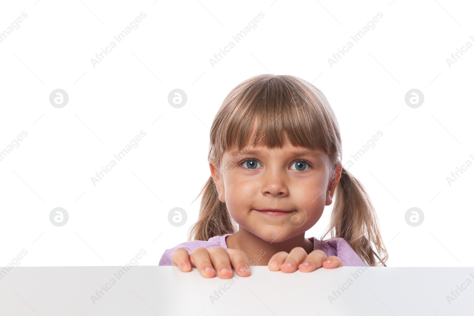 Photo of Curious little girl peeking over table against white background
