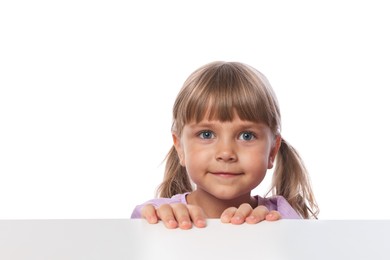Photo of Curious little girl peeking over table against white background