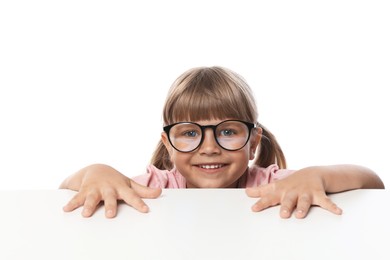 Photo of Curious little girl peeking in glasses over table against white background