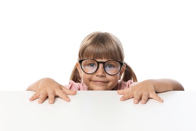 Photo of Curious little girl peeking in glasses over table against white background