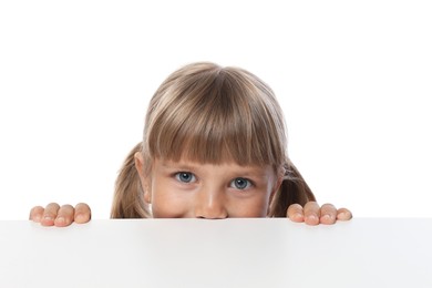 Photo of Curious little girl peeking over table against white background