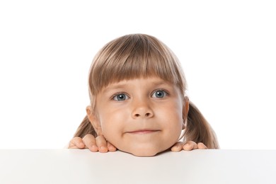Photo of Curious little girl peeking over table against white background