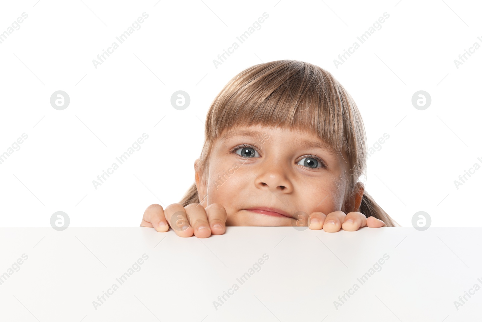 Photo of Curious little girl peeking over table against white background