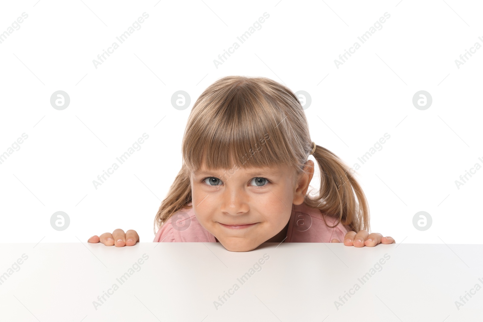 Curious little girl peeking over table against white background Photo of Curious little girl peeking over table against white background