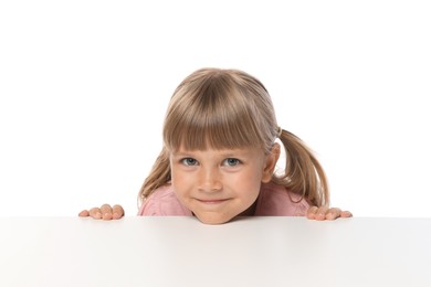 Photo of Curious little girl peeking over table against white background