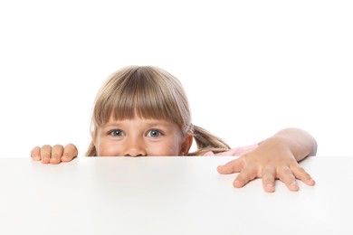 Photo of Curious little girl peeking over table against white background