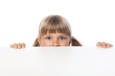 Photo of Curious little girl peeking over table against white background