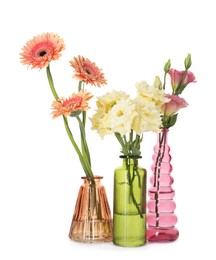 Photo of Different beautiful flowers in glass vases isolated on white