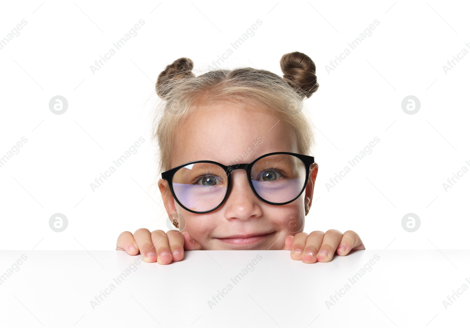 Photo of Curious little girl in glasses peeking over table against white background