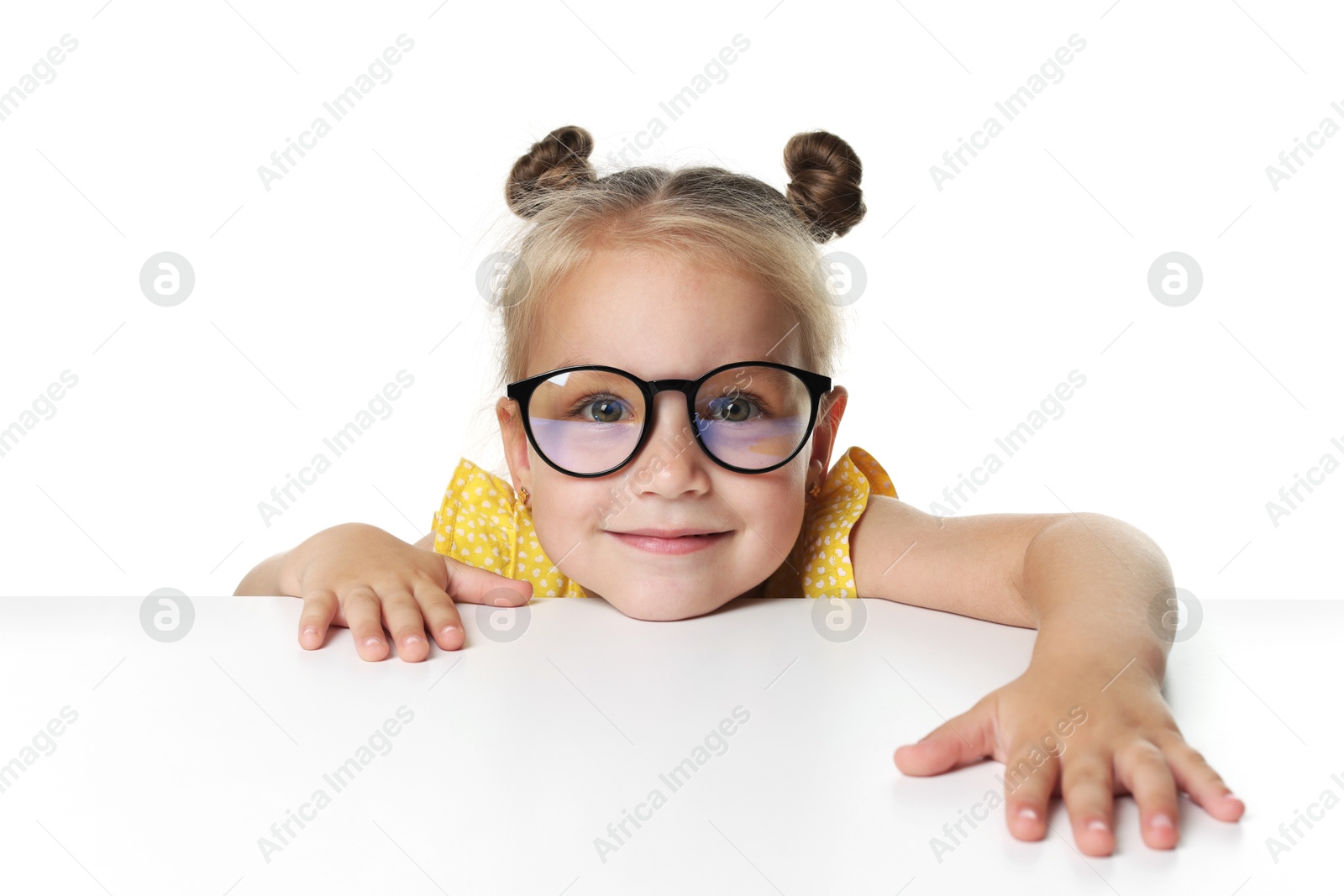 Photo of Curious little girl in glasses peeking over table against white background