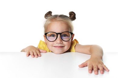 Photo of Curious little girl in glasses peeking over table against white background